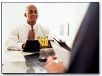 Man at desk talking with another man